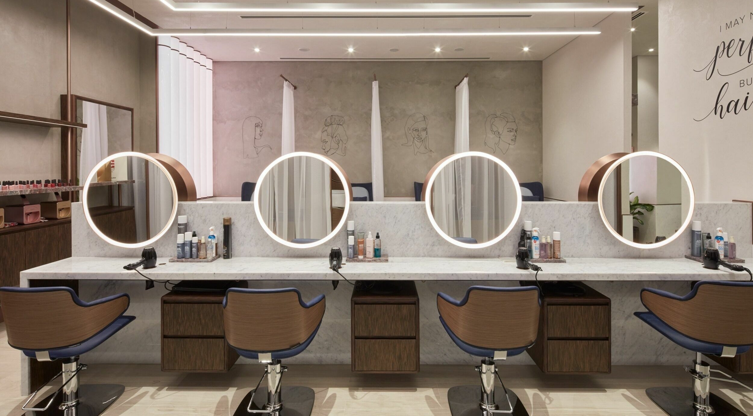 Elegant salon space at Rose Poudre Beauty Bar with modern mirrors and styling chairs in Abu Dhabi, AE.