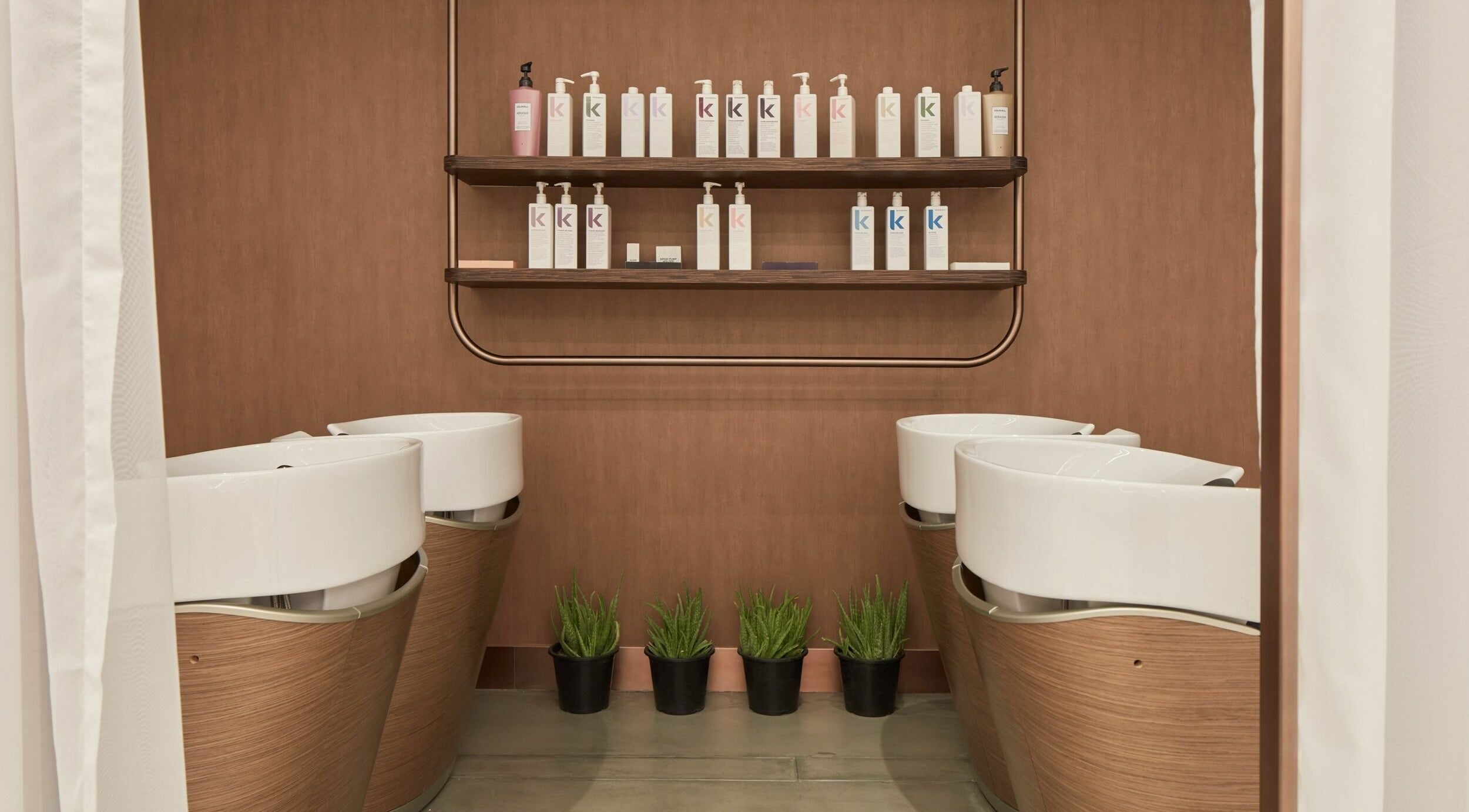 Chic hair washing area at Rose Poudre Beauty Bar, Abu Dhabi, AE, with elegant basins and stylish product display.