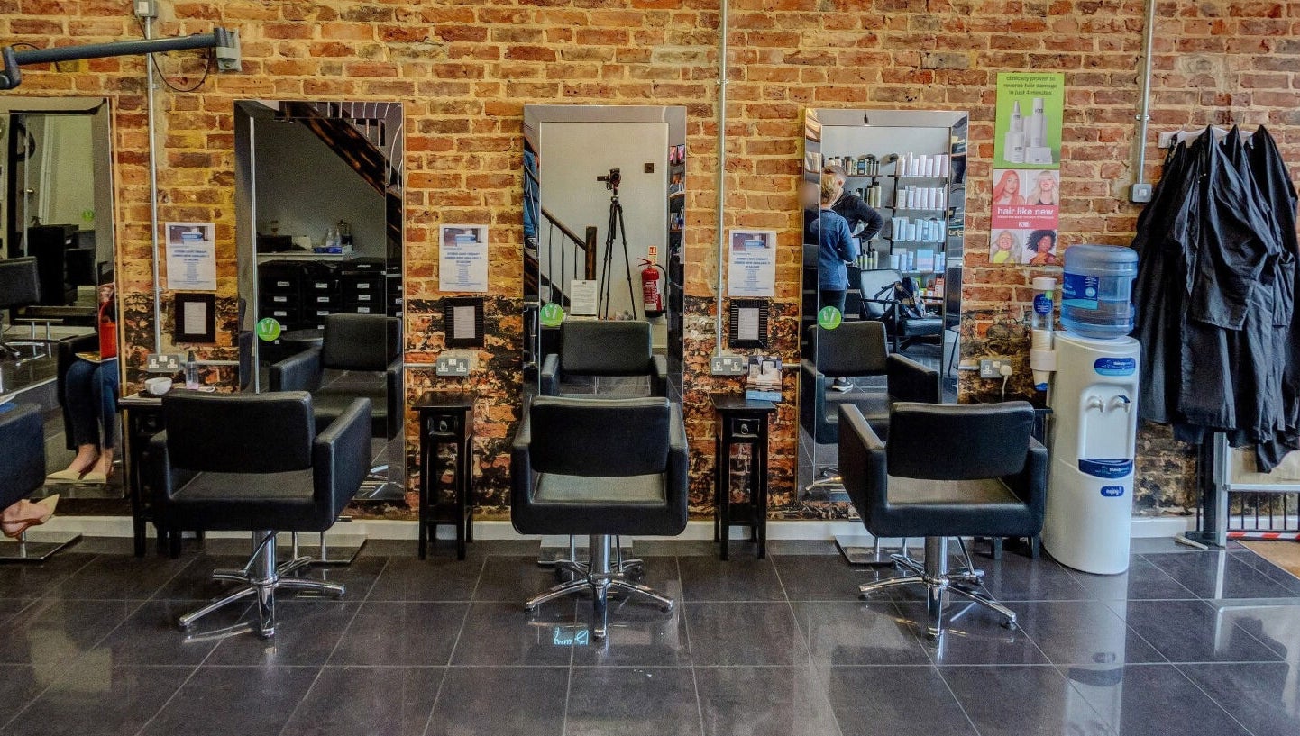 Modern salon chairs and mirrors at Jonathan Ditton salons in Emsworth, England, GB with exposed brick walls.