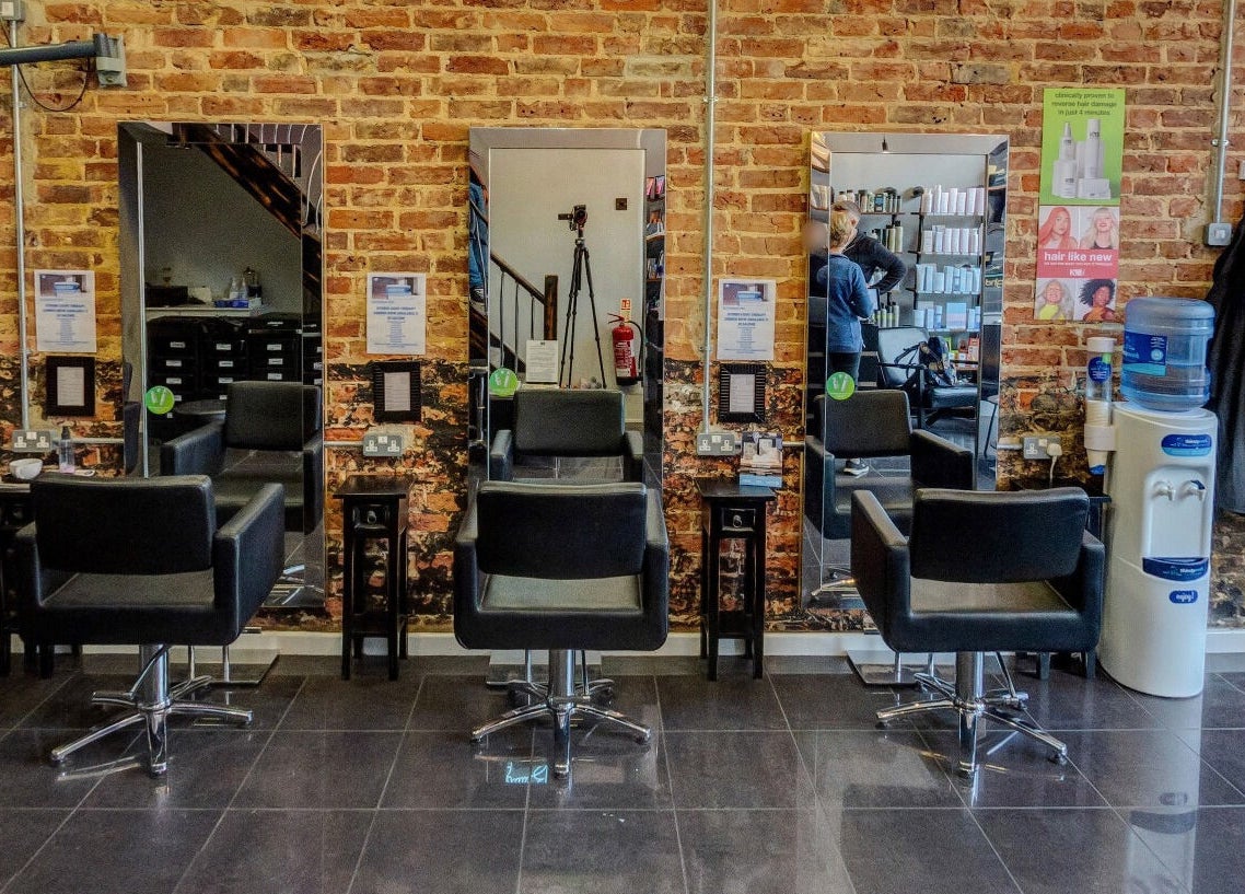 Modern salon chairs and mirrors at Jonathan Ditton salons in Emsworth, England, GB with exposed brick walls.