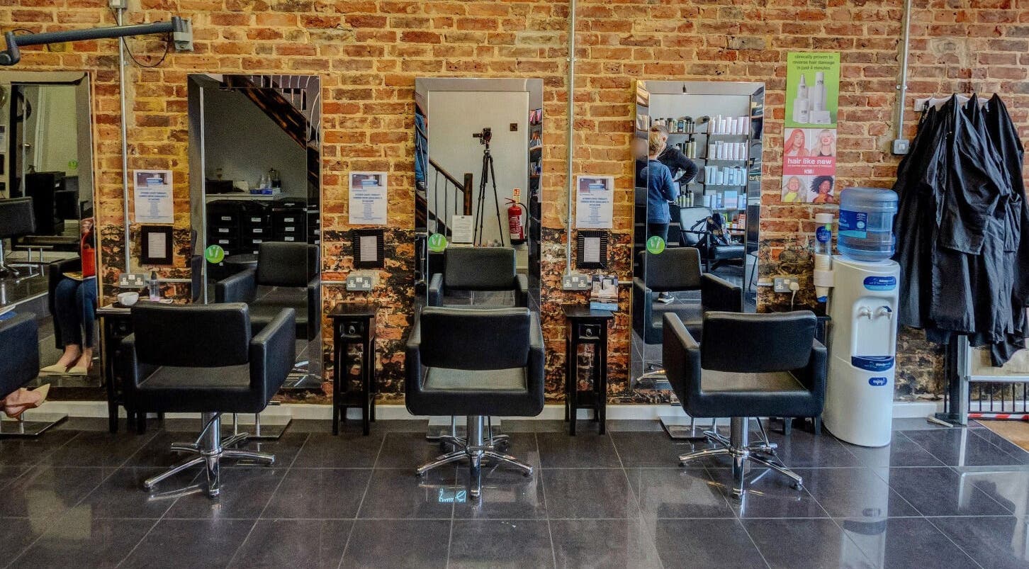 Modern salon chairs and mirrors at Jonathan Ditton salons in Emsworth, England, GB with exposed brick walls.