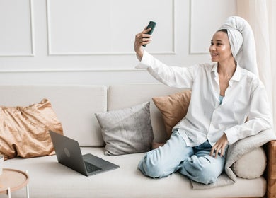 Woman enjoying Staycation Mobile Spa at home in Farmersville, Texas, US, taking a selfie while relaxing on sofa.