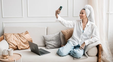 Woman enjoying Staycation Mobile Spa at home in Farmersville, Texas, US, taking a selfie while relaxing on sofa.