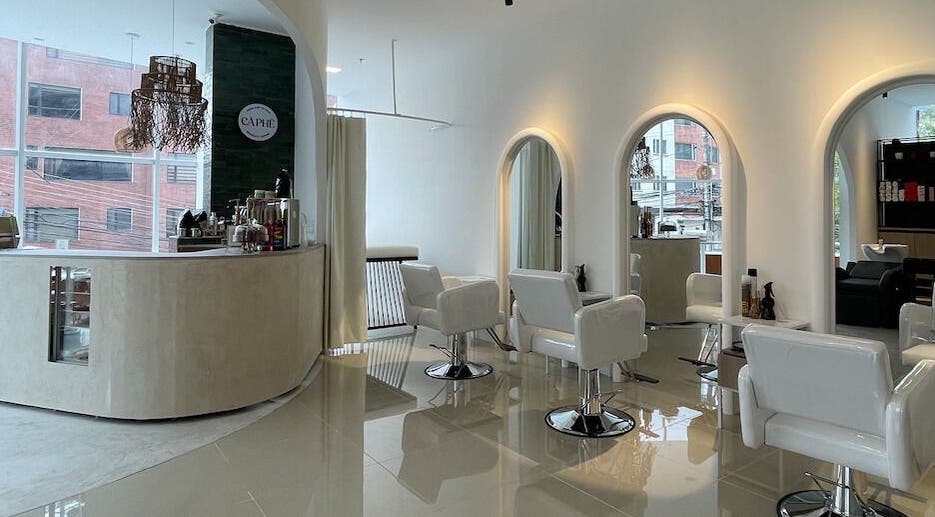 Interior moderno de Brushed Beauty Bar Quito Tennis en Quito, Pichincha, EC con sillas blancas y luces suaves.