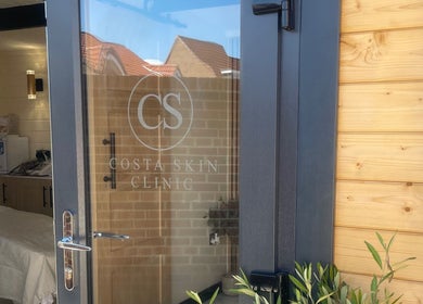Entrance of Costa Skin Clinic in Alnwick, England, GB with glass door and wooden walls.