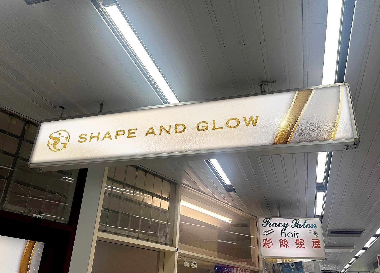 Illuminated sign for Shape and Glow, Blacktown, NSW, AU, under a modern, well-lit ceiling.