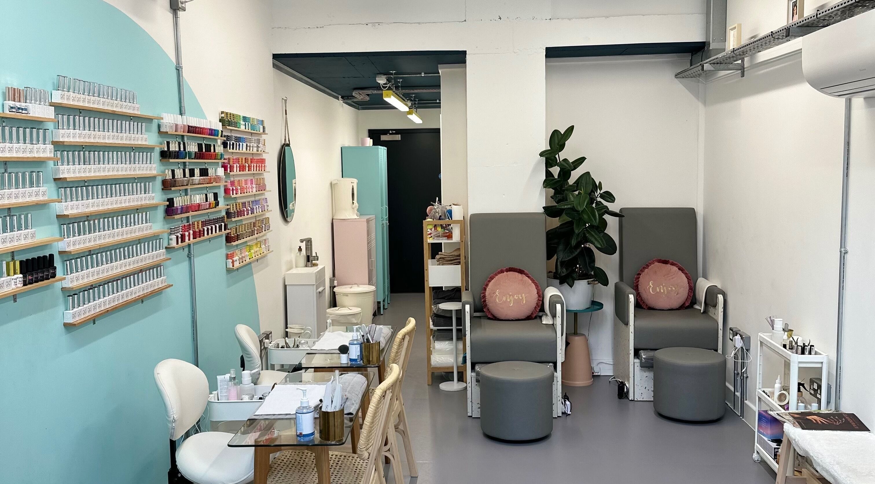 Interior of Kushty Beauty in London, England, GB featuring nail polish displays and comfortable seating.