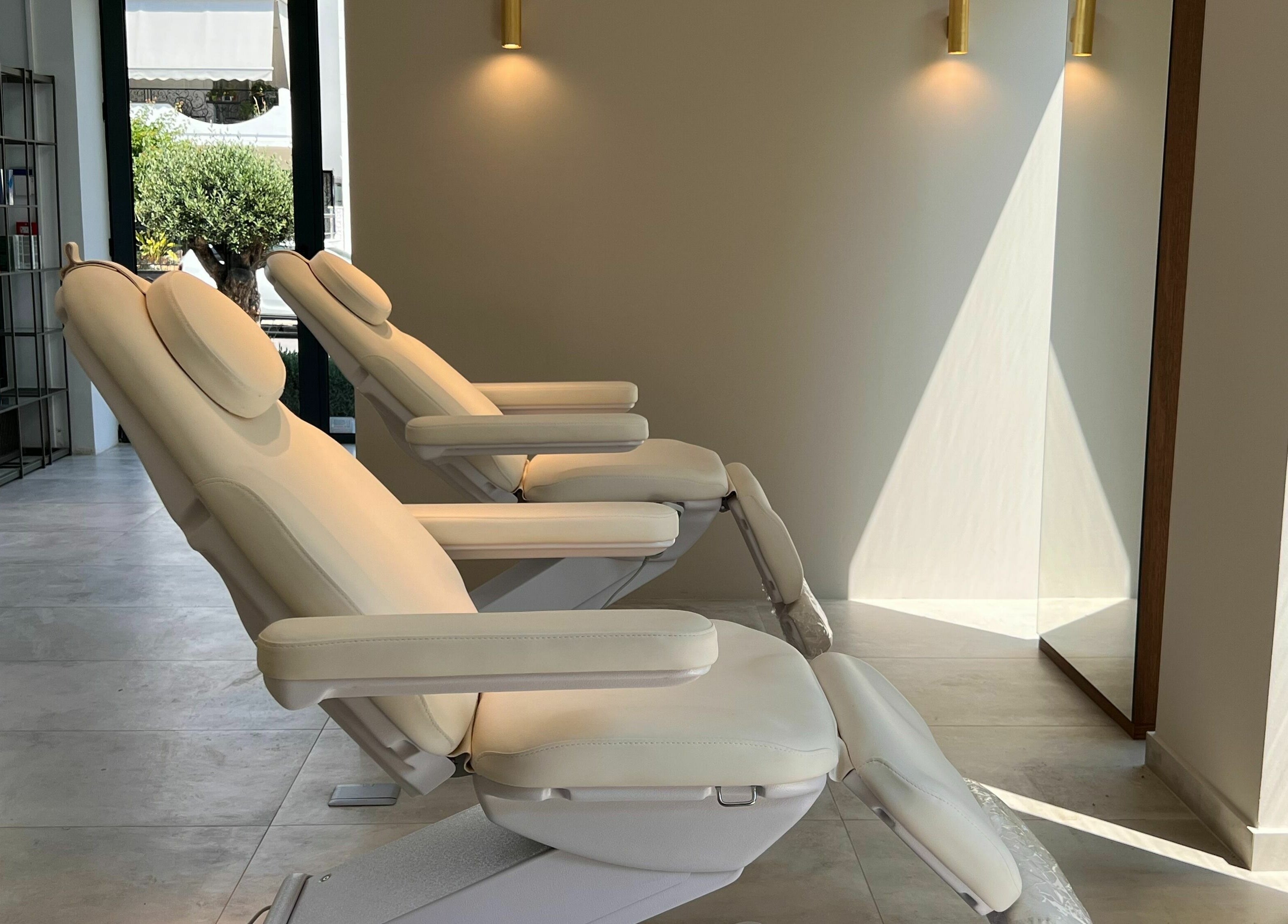 Luxurious reclining chairs inside Face It Mind Skin Bar, Glifada, GR, bathed in soft sunlight.