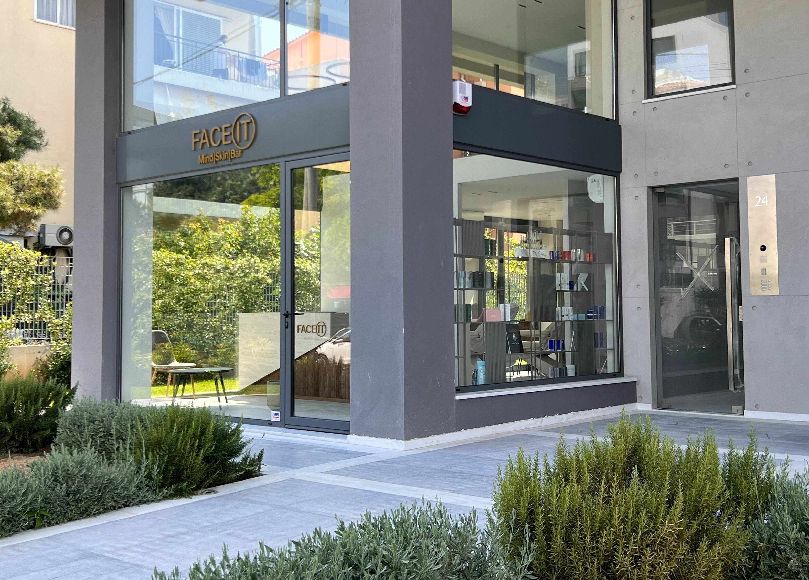 Entrance to Face It Mind Skin Bar in Glifada, GR surrounded by lush greenery.