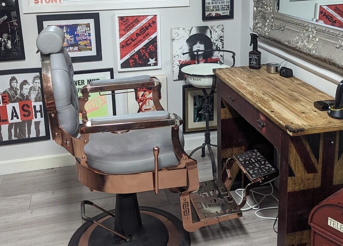 Stylish barber chair and rustic decor at Fred's Barbers, Crawley, England, GB flaunting vintage posters.