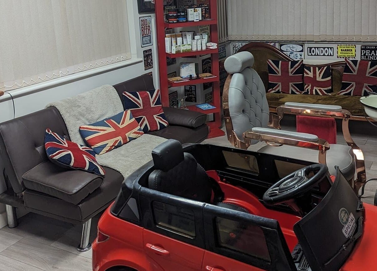British-themed seating area at Fred's Barbers, Crawley, England, GB with Union Jack pillows.