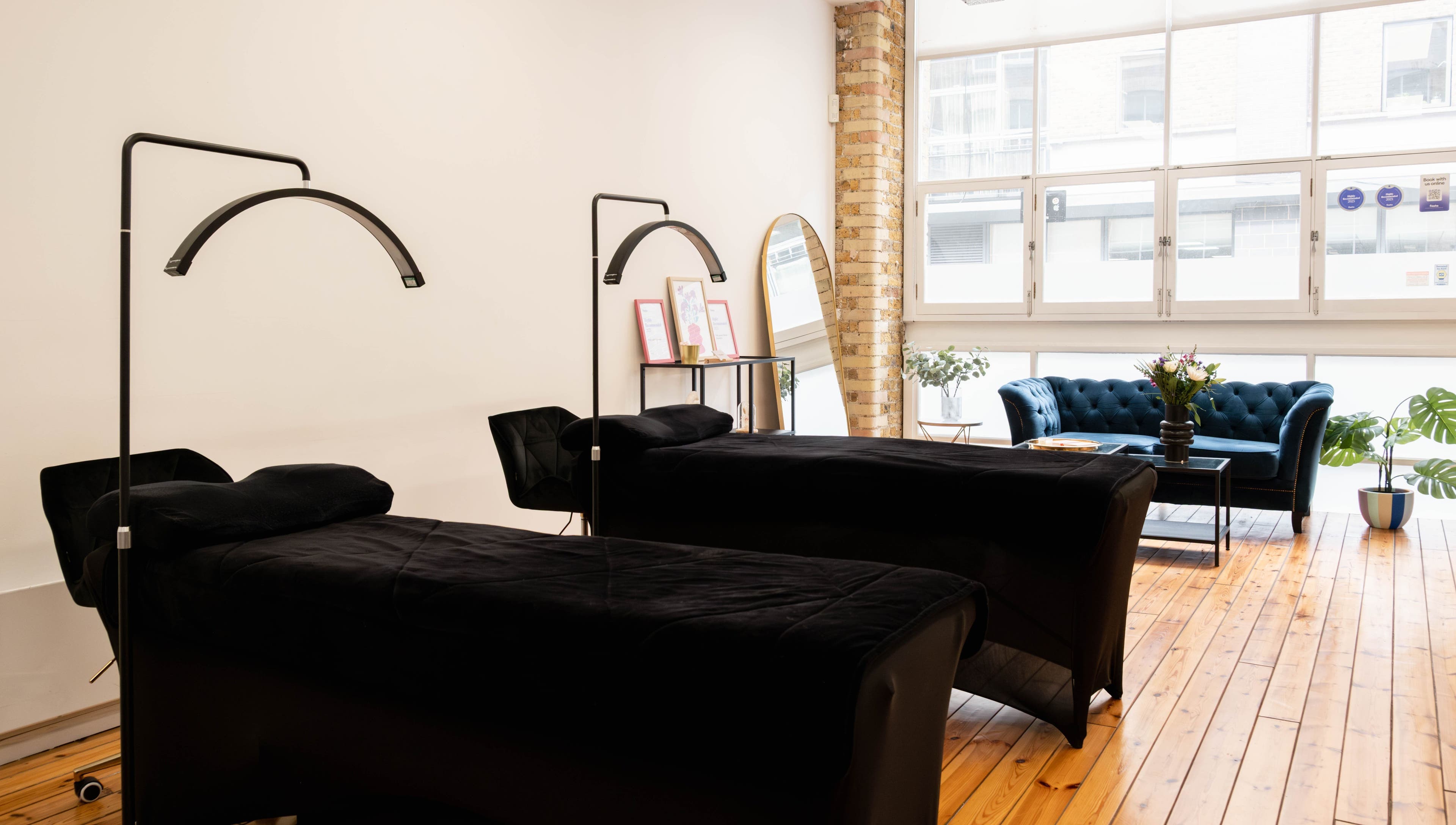 Relaxing treatment room at Polly Lashes & Brows London, featuring comfortable beds and cozy seating in London, England, GB.