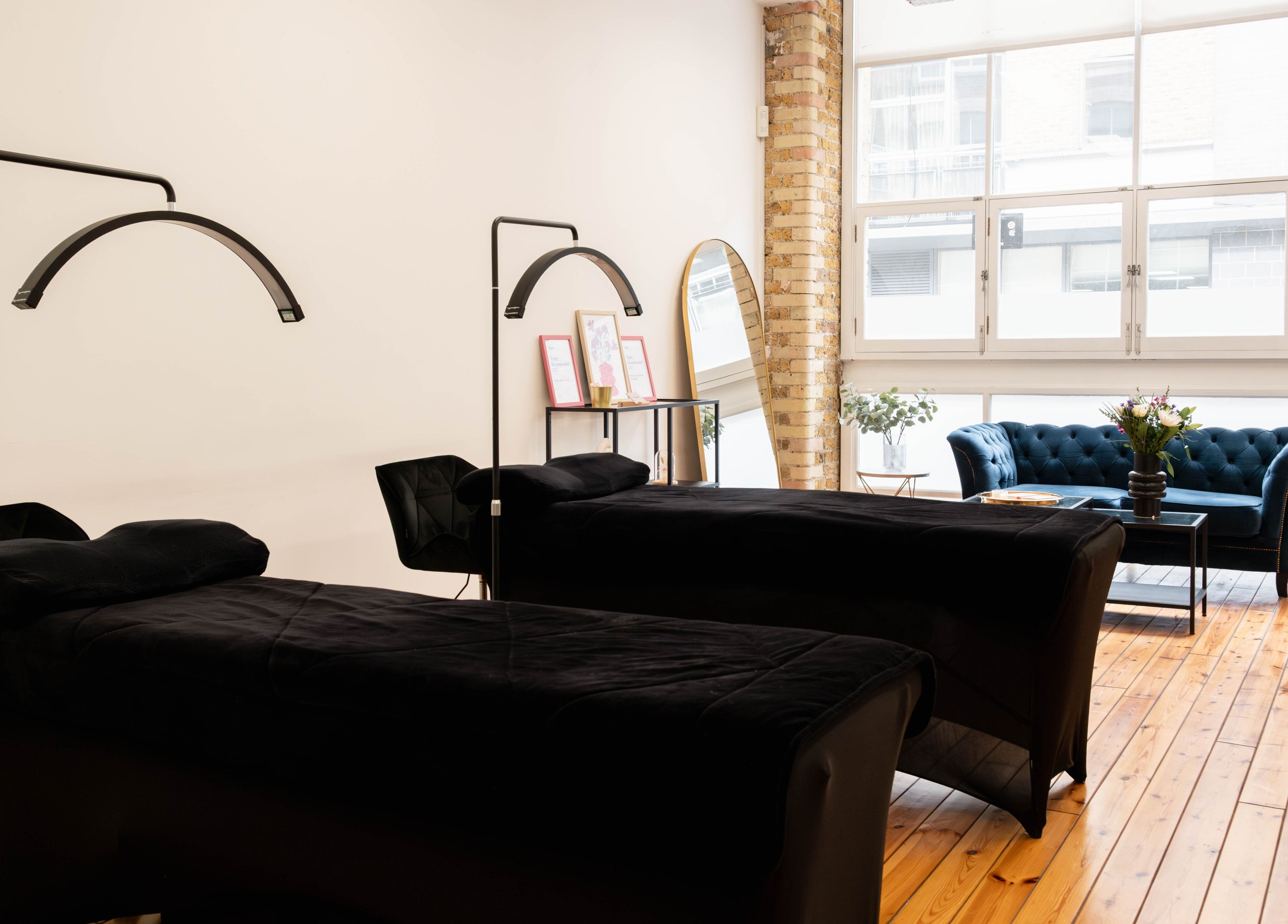 Relaxing treatment room at Polly Lashes & Brows London, featuring comfortable beds and cozy seating in London, England, GB.
