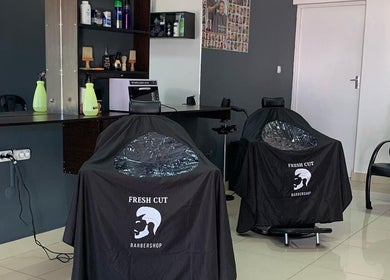 Interior moderno do Fresh Cut Barbershop em Maputo, Maputo, MZ, apresentando cadeiras e produtos de barbearia.