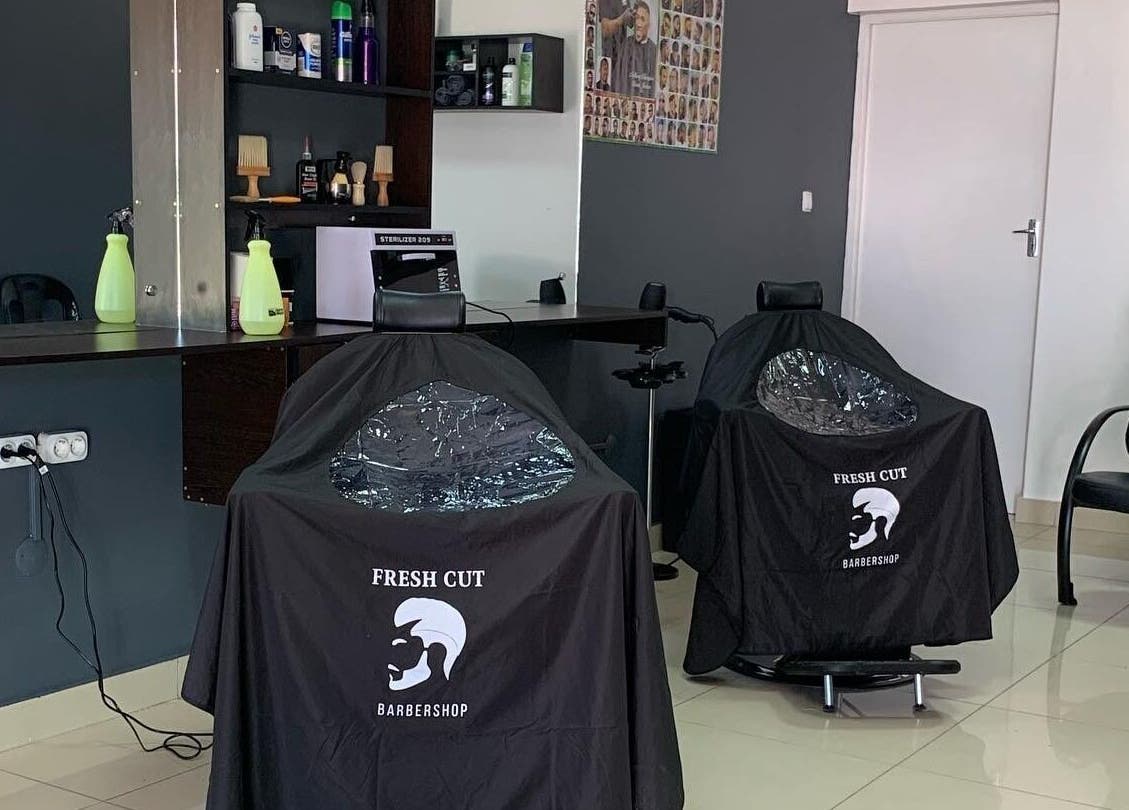 Interior moderno do Fresh Cut Barbershop em Maputo, Maputo, MZ, apresentando cadeiras e produtos de barbearia.