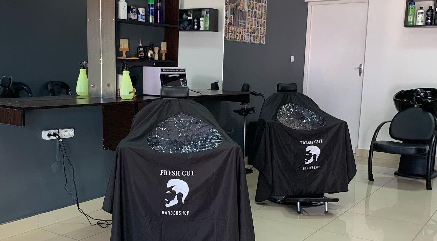 Interior moderno do Fresh Cut Barbershop em Maputo, Maputo, MZ, apresentando cadeiras e produtos de barbearia.