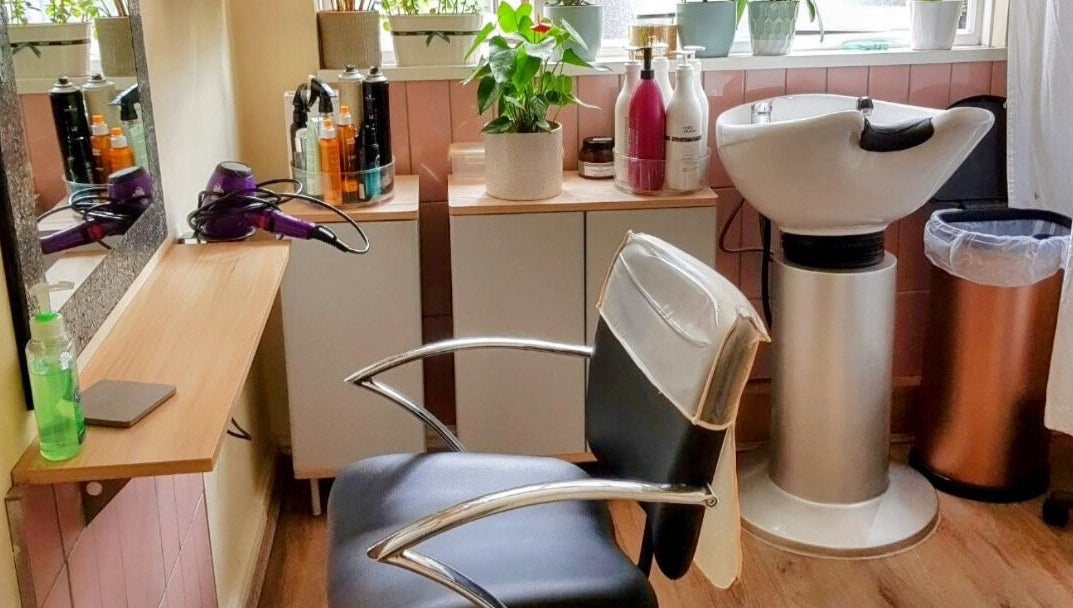 Stylish salon interior at Hair by Elena P in London, England, GB featuring a modern chair and washing station.