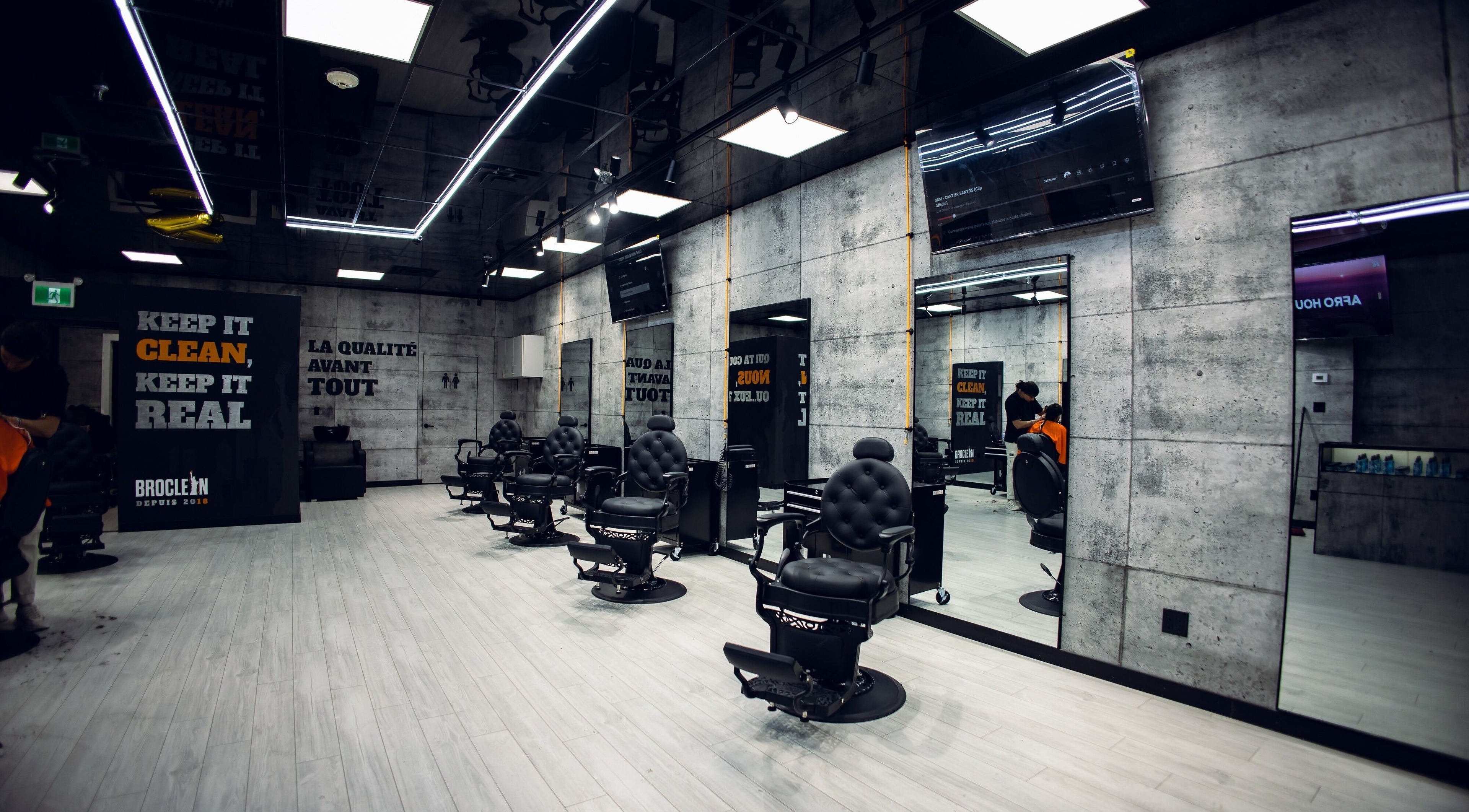 Intérieur moderne de Broclean Barbershop à Longueuil, Québec, CA avec fauteuils élégants et slogans motivants.