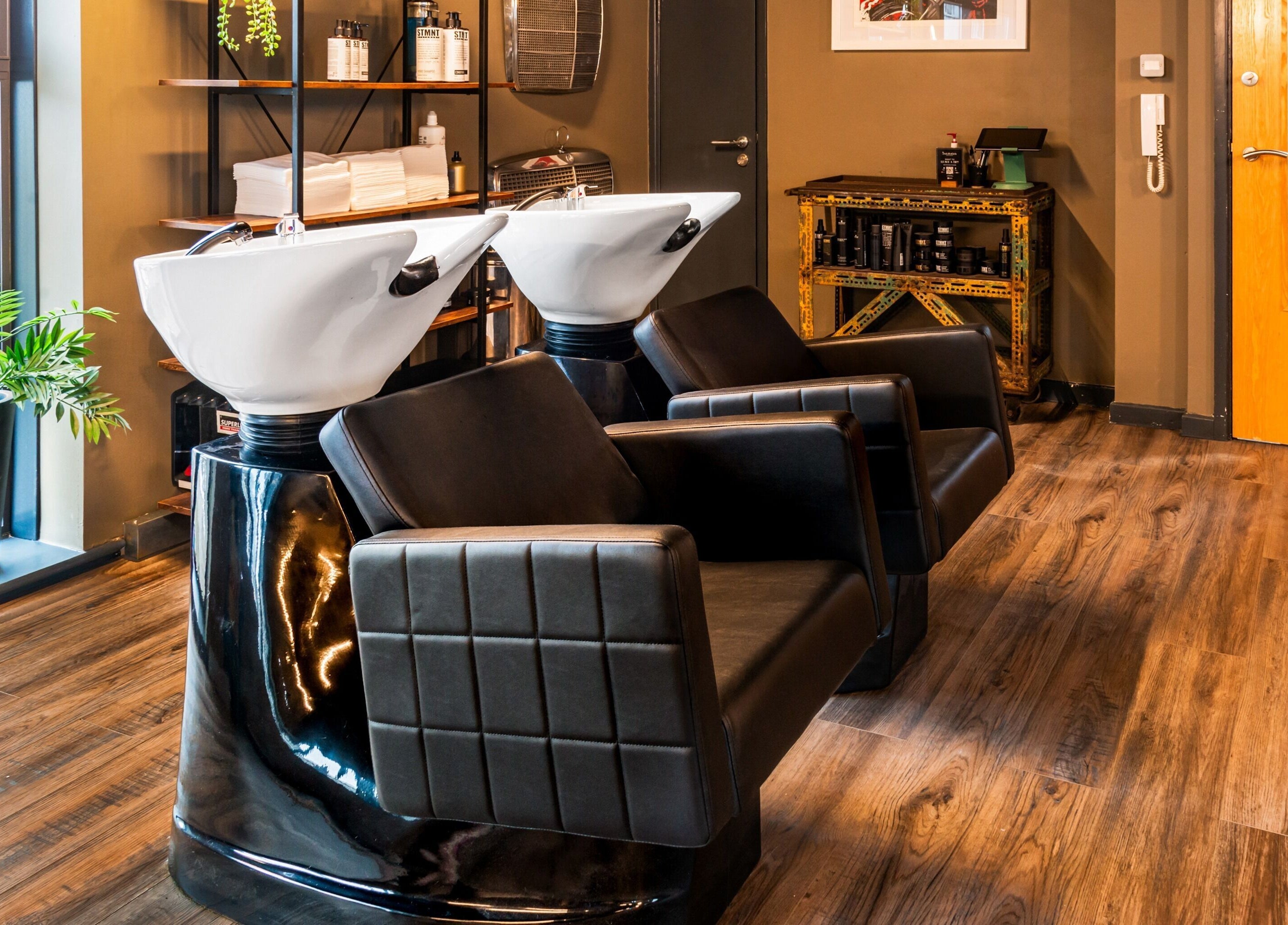 Modern wash stations at Boilerhouse Gentleman - Ouseburn, Newcastle upon Tyne, England, GB. Sleek black leather seating.