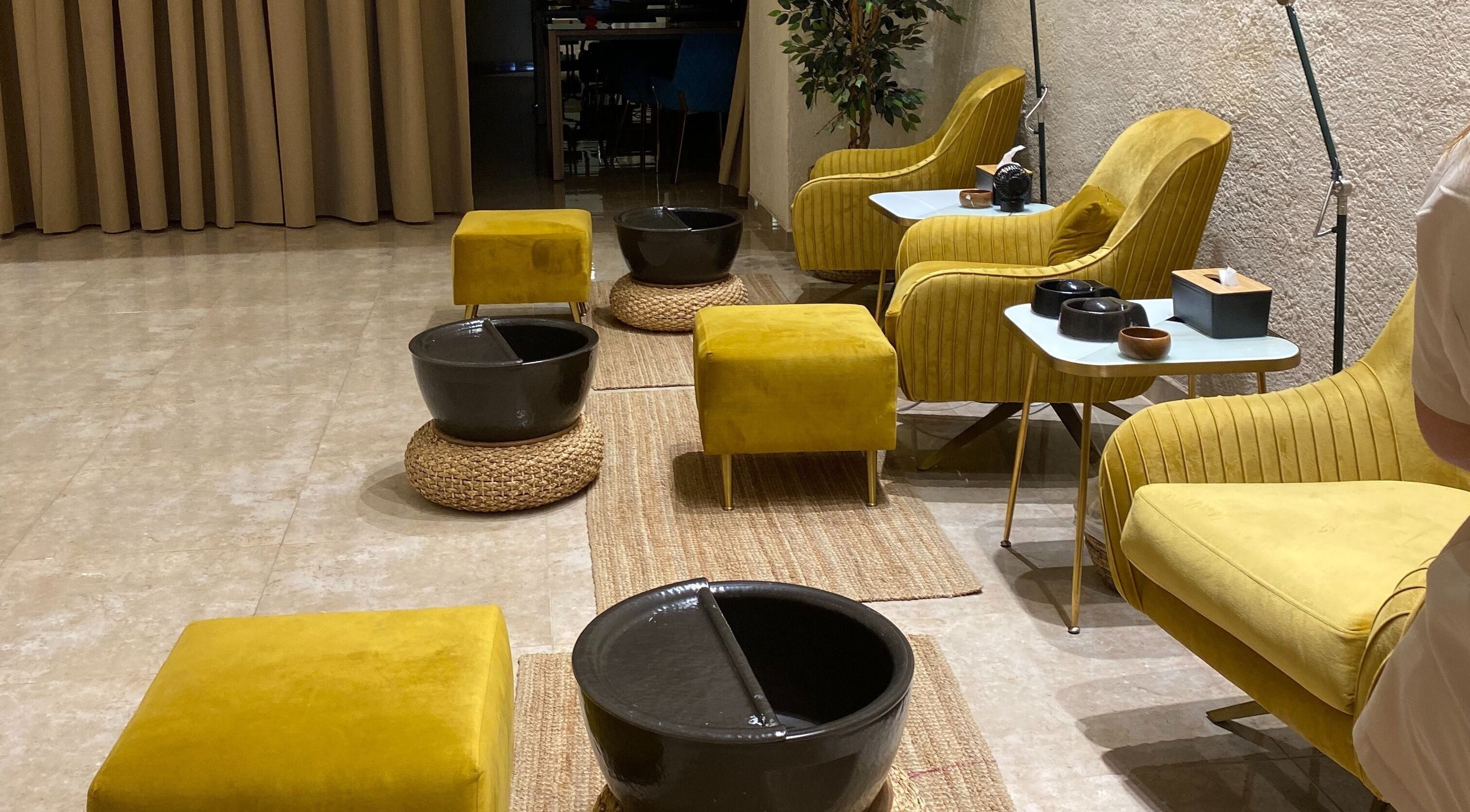 Cozy pedicure setup at The Bliss Nails, Riyadh, SA with plush yellow seating and elegant decor.