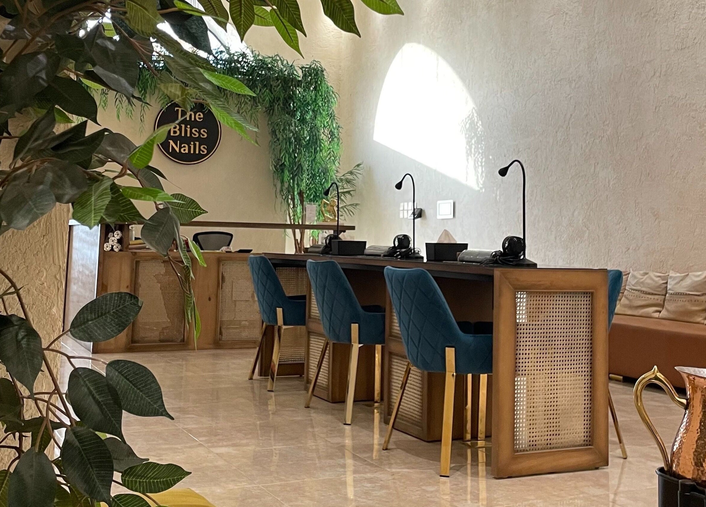 Interior view of The Bliss Nails salon in Riyadh, SA showcasing elegant nail stations and lush greenery.