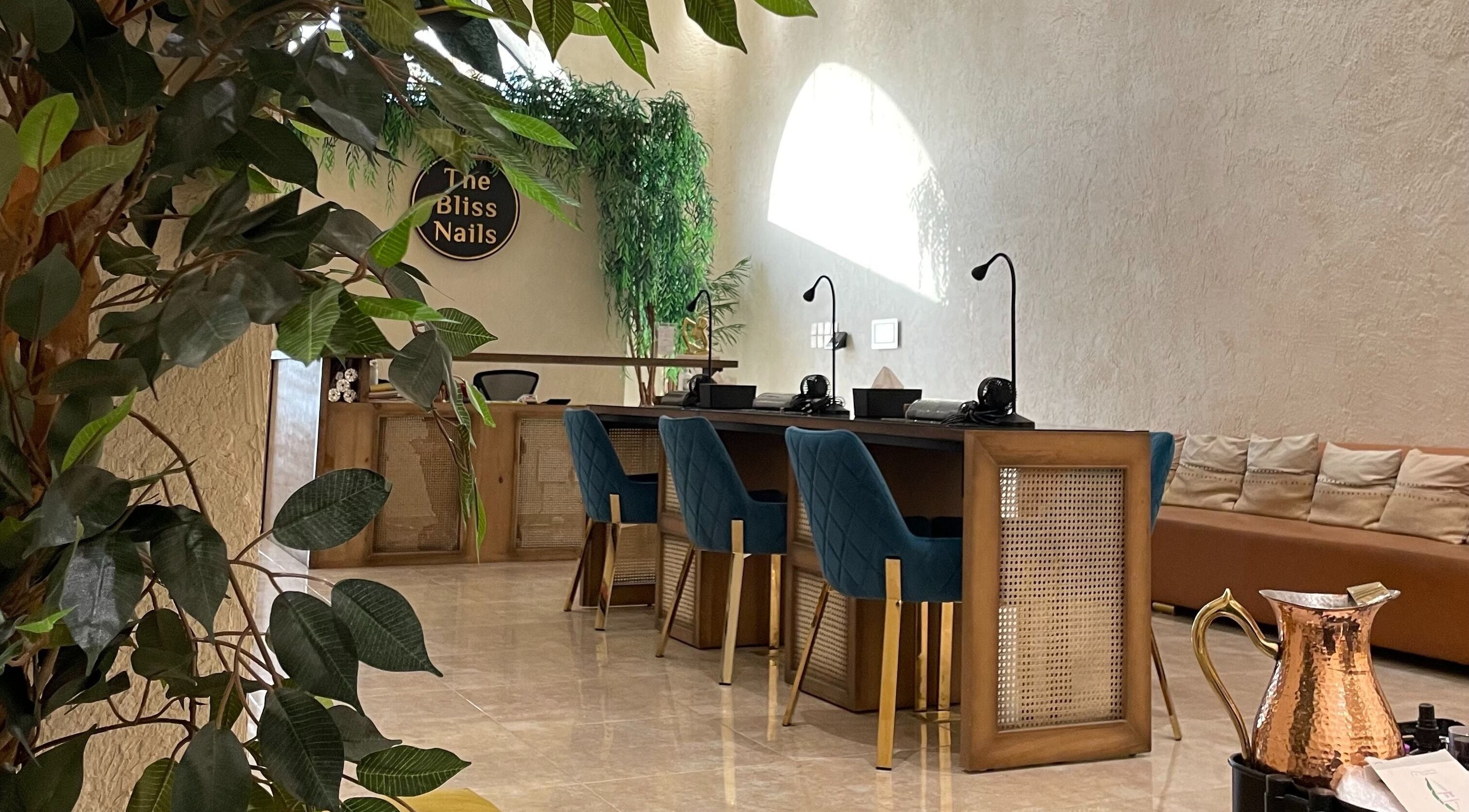 Interior view of The Bliss Nails salon in Riyadh, SA showcasing elegant nail stations and lush greenery.