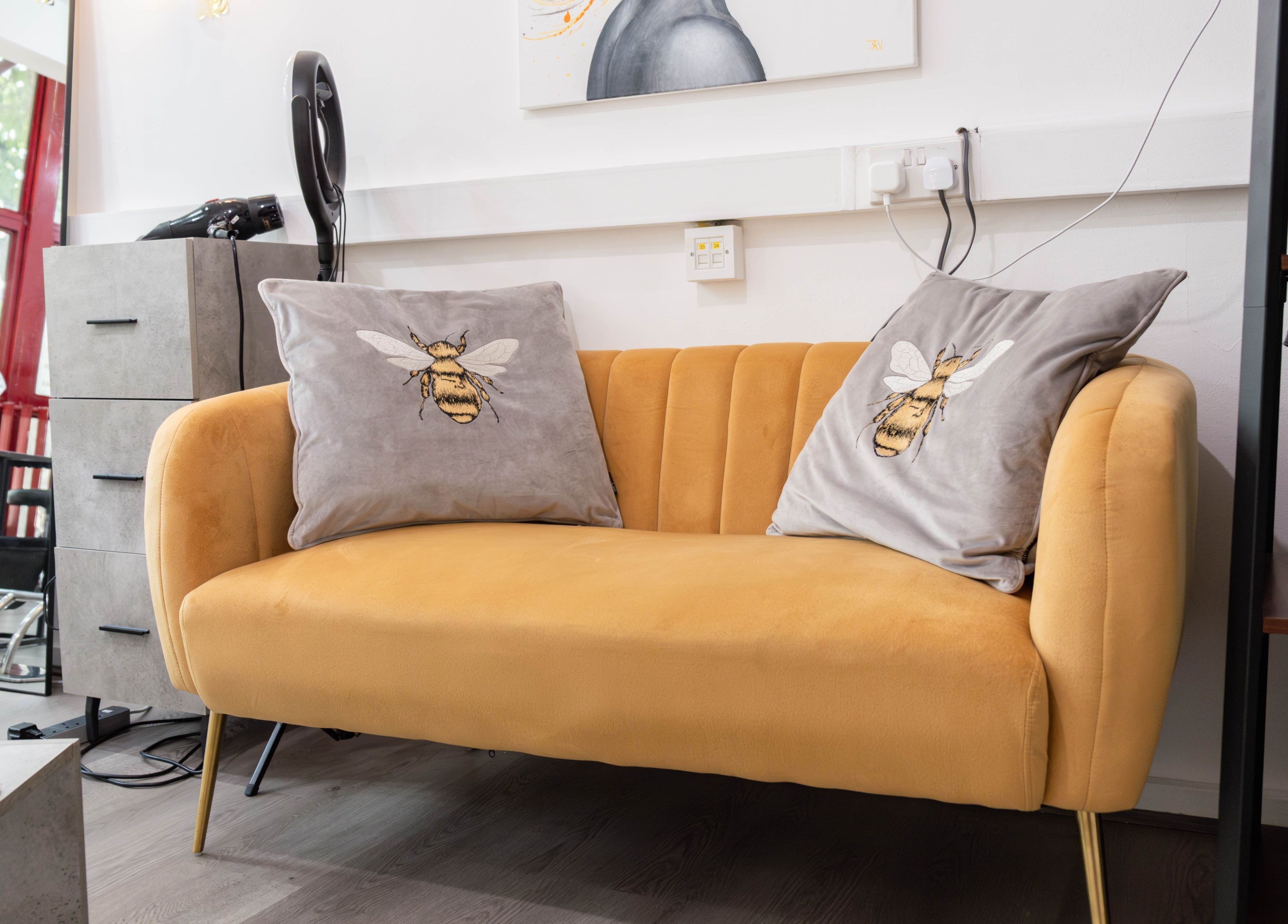 Cozy yellow sofa with bee pillows at Hair Rituals by Ariana in London, England, GB.