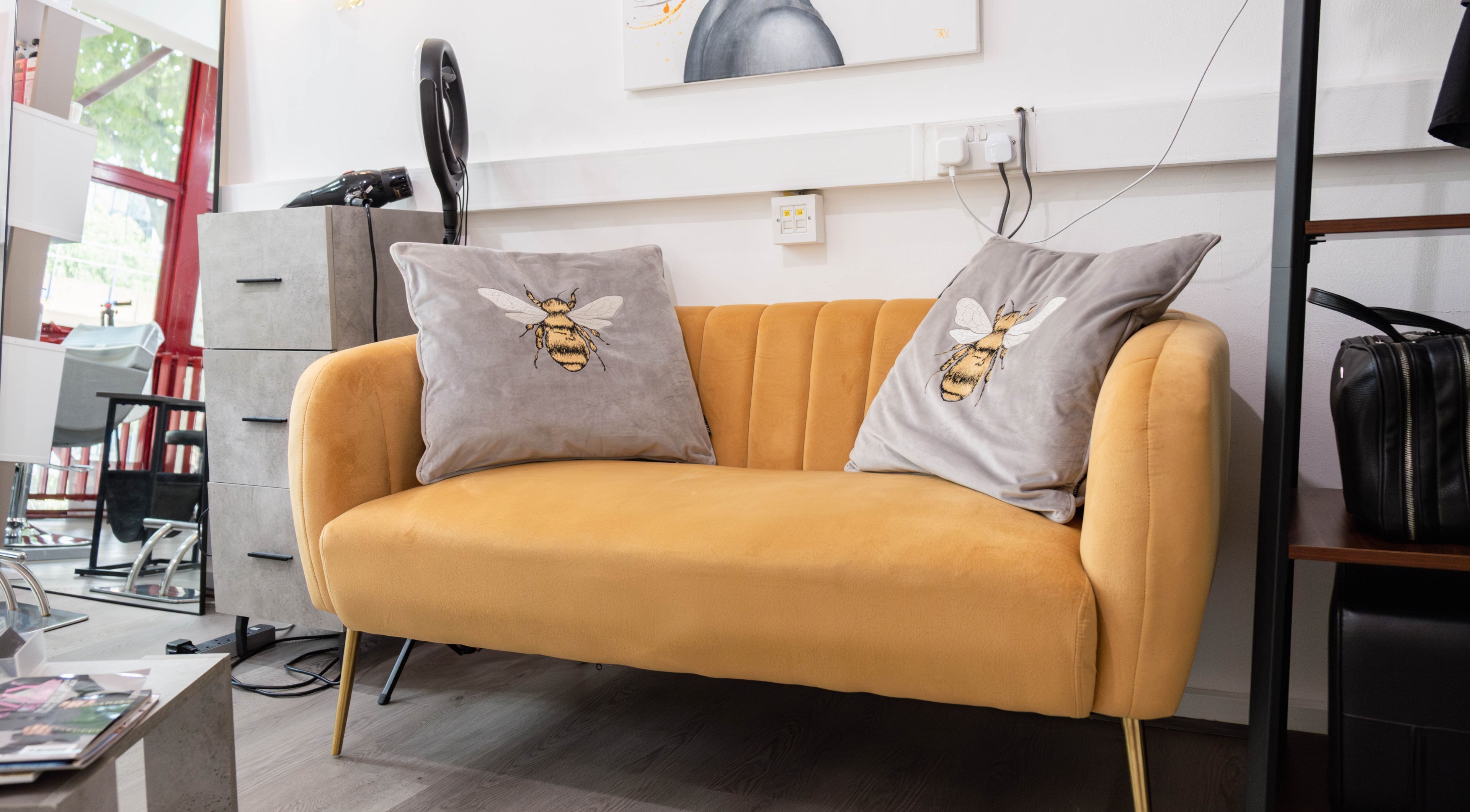 Cozy yellow sofa with bee pillows at Hair Rituals by Ariana in London, England, GB.