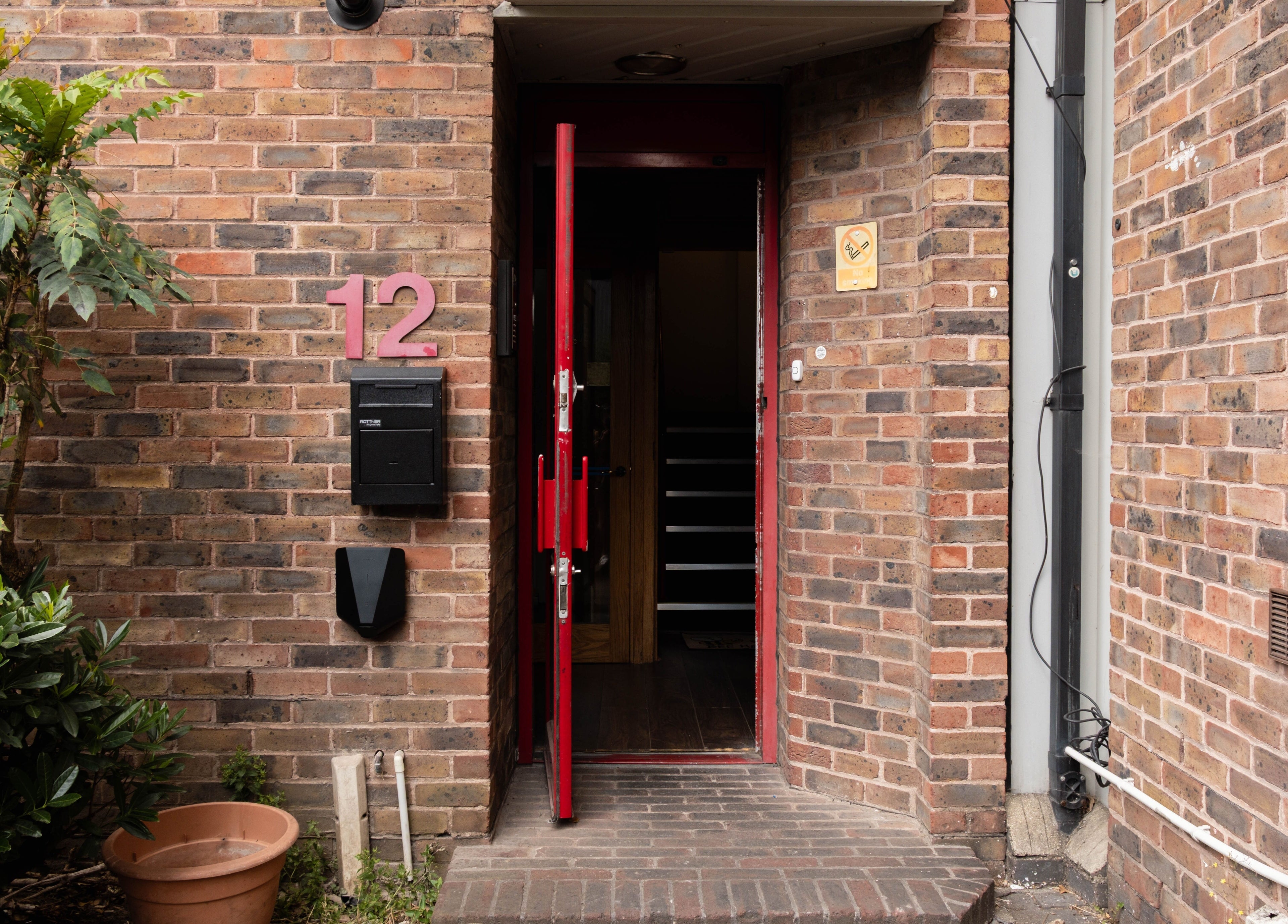 Entrance to Hair Rituals by Ariana in London, England, GB, with red door and brick wall.