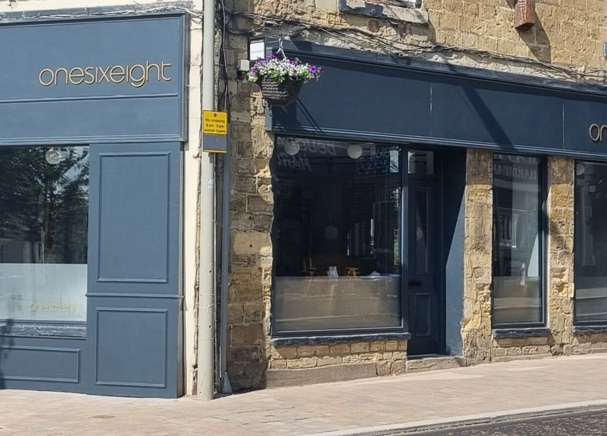 Exterior of Onesixeight beauty spa in Boston Spa, England with classic stone and navy blue design.