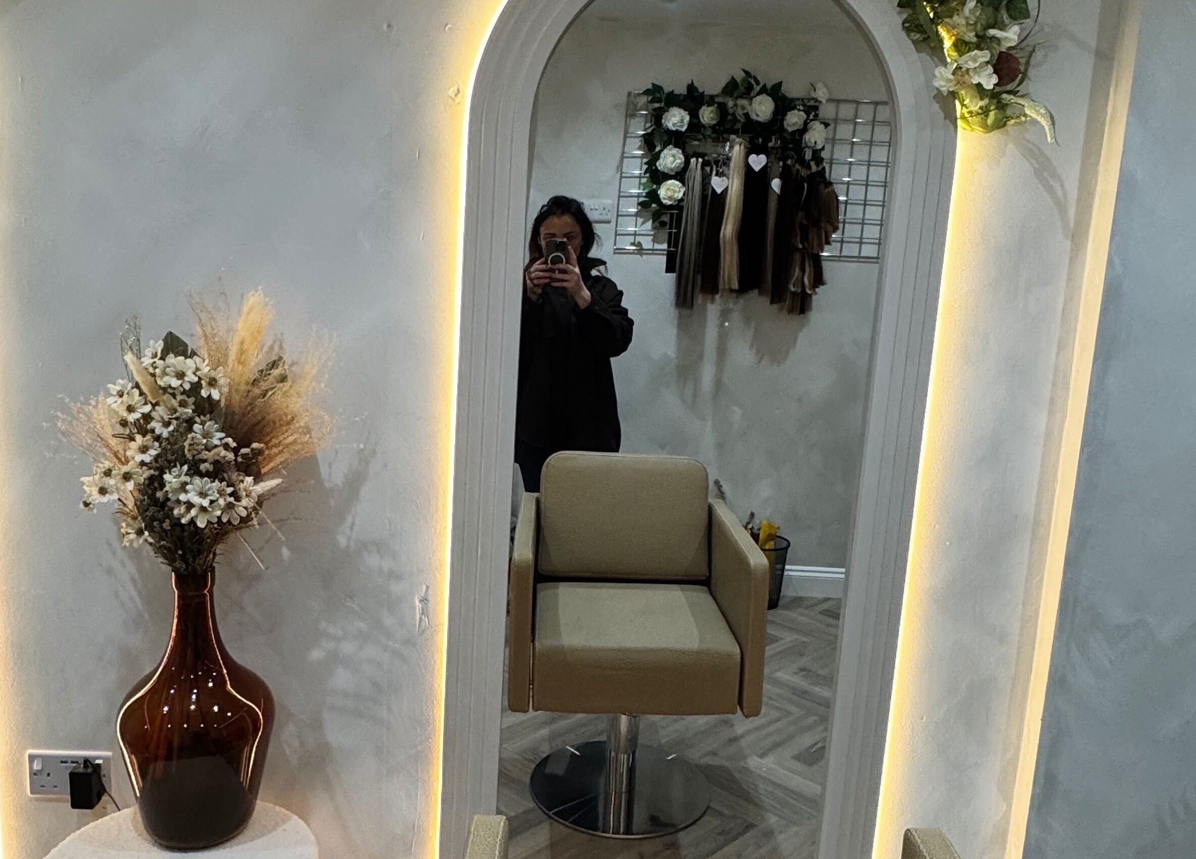 Cozy salon corner at Valentina Hair and Skin, Sandbach, England, GB with illuminated mirror and floral decor.