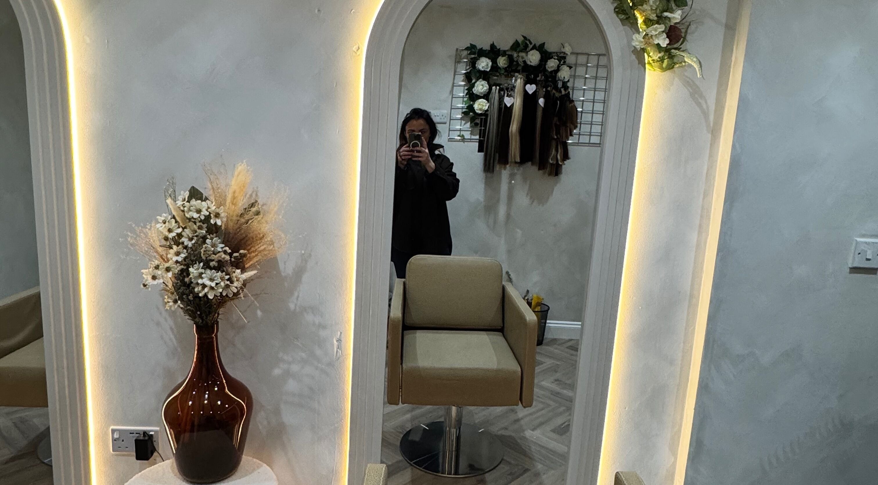 Cozy salon corner at Valentina Hair and Skin, Sandbach, England, GB with illuminated mirror and floral decor.