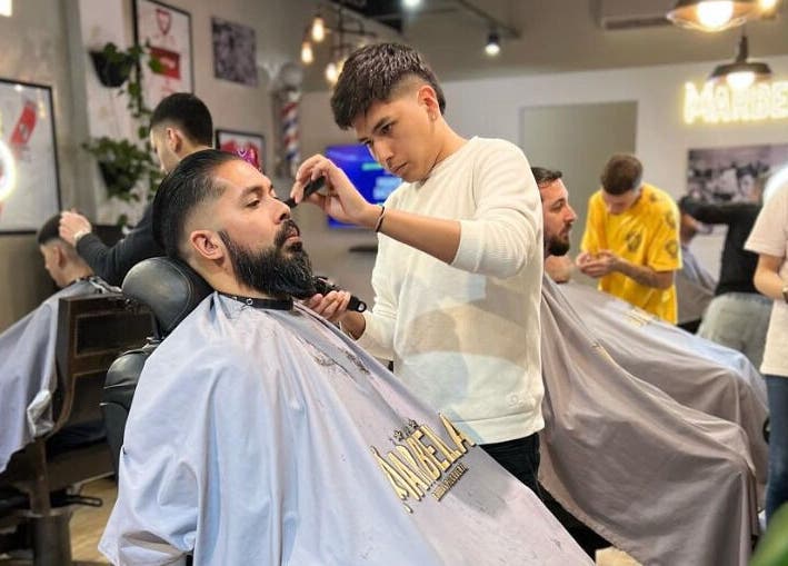 Barbero en Marbella Barberia y Peluqueria en Udaondo, Provincia de Buenos Aires, AR, realizando un corte de cabello.