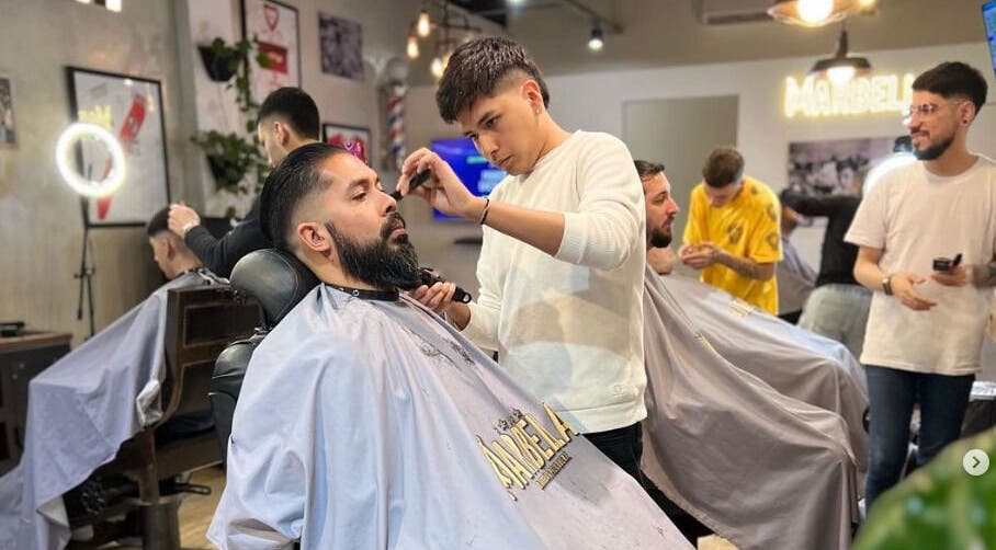 Barbero en Marbella Barberia y Peluqueria en Udaondo, Provincia de Buenos Aires, AR, realizando un corte de cabello.