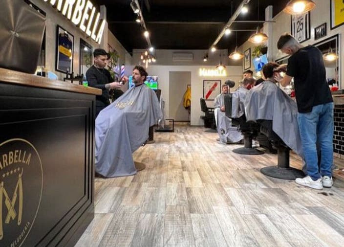 Interior moderno de Marbella Barberia y Peluqueria en Udaondo, Provincia de Buenos Aires, AR con clientes y barberos.