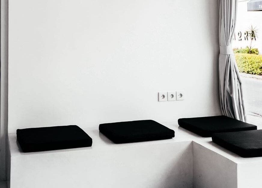 Sleek seating area at Laser Me in Bali, Bali, ID with black cushions on white benches.