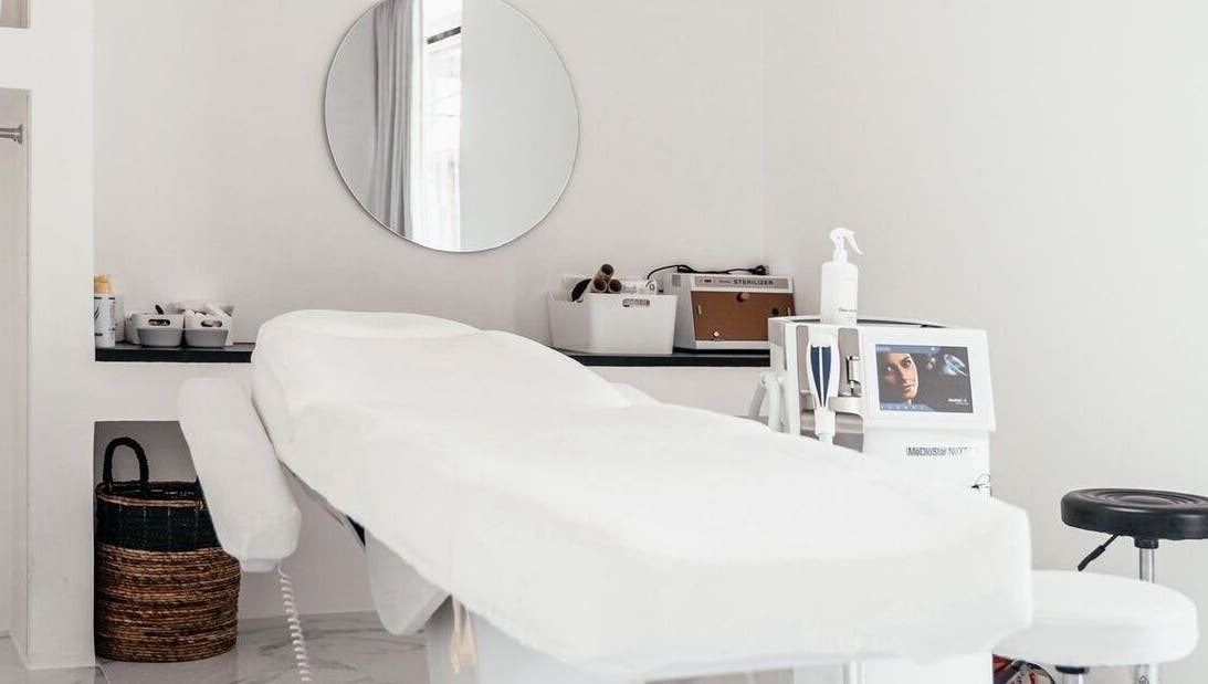 Modern treatment room at LASER ME ULUWATU in Bali, Bali, ID with a sleek massage bed and round mirror.