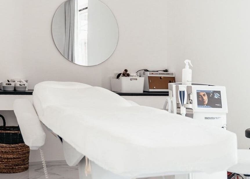 Modern treatment room at LASER ME ULUWATU in Bali, Bali, ID with a sleek massage bed and round mirror.