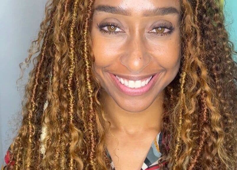 Radiant smile at Savoir Beauty Ltd, Point Fortin, TT, showcasing beautiful curly hair and vibrant ambiance.