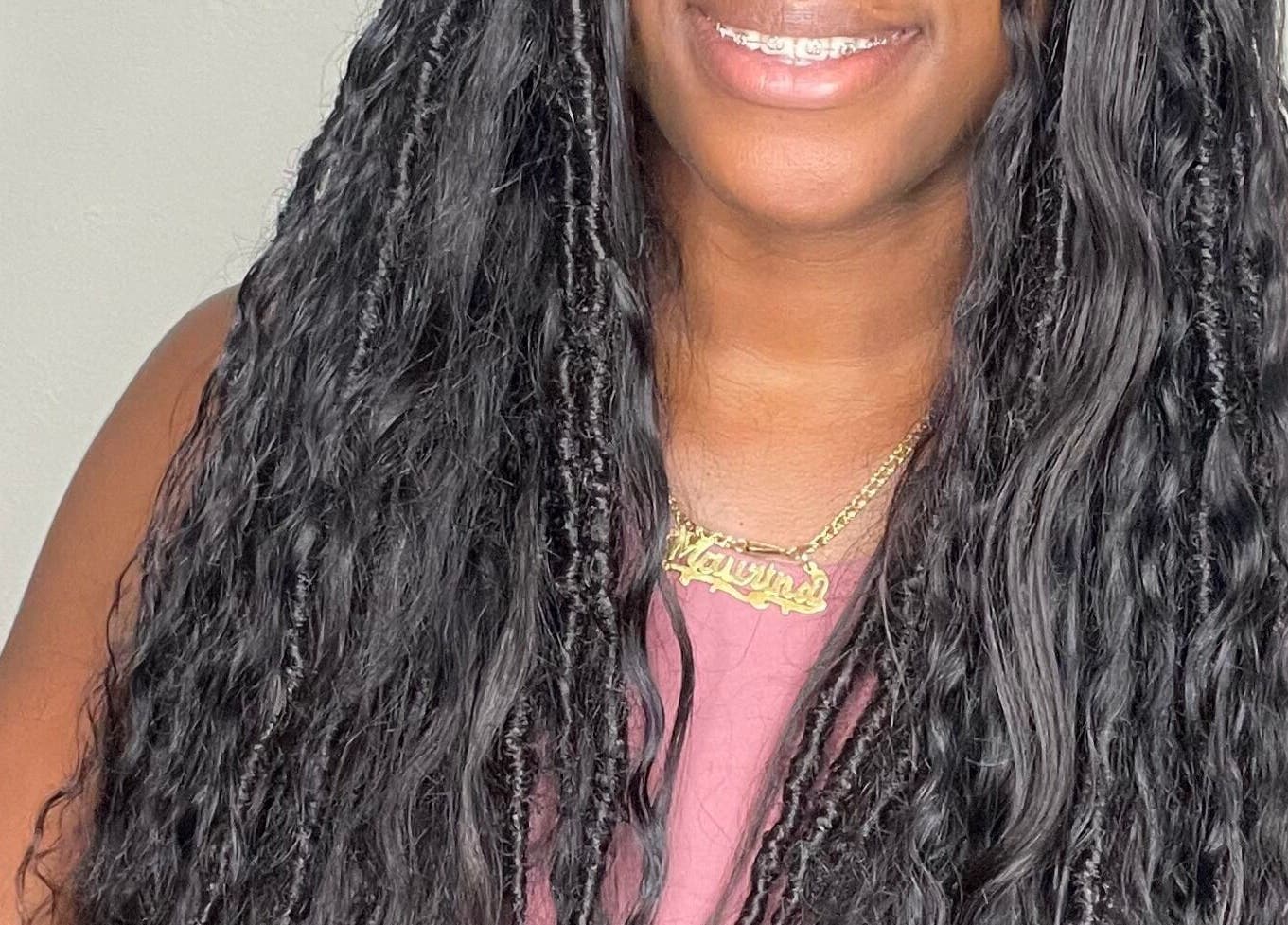 Smiling individual at Savoir Beauty Ltd, Point Fortin, TT, showcasing stylish long, curly hair.