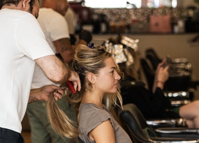 Stylist crafting a chic hairstyle at TOQQA Hair Salon, London, England, GB, with clients engaged in relaxation.