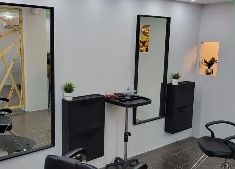 Interior moderno de Cortauñas Salón en Carolina, US con sillas negras y espejo elegante.