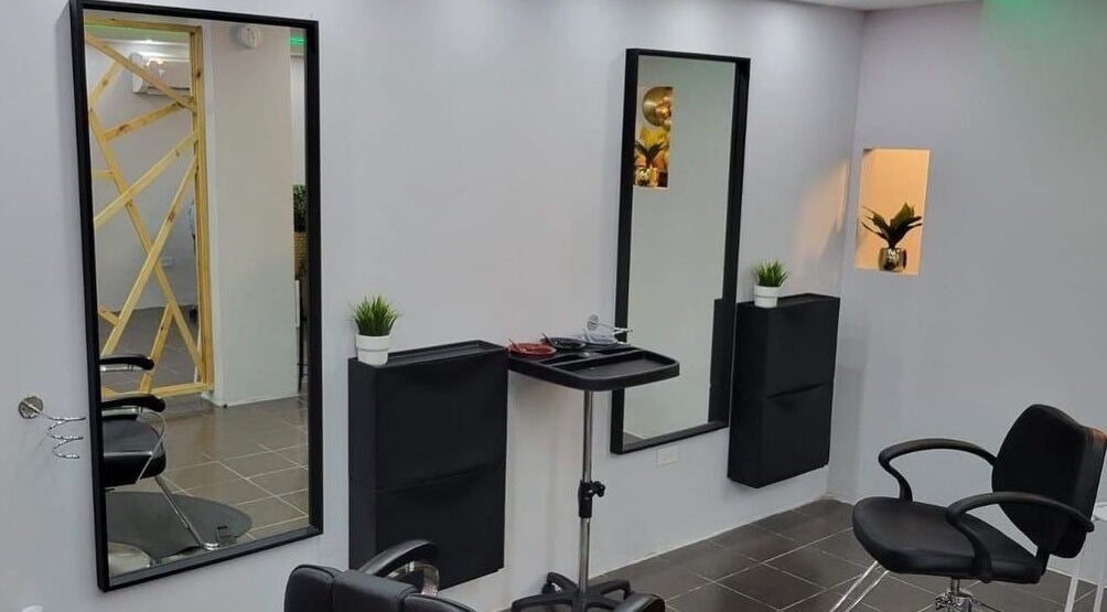 Interior moderno de Cortauñas Salón en Carolina, US con sillas negras y espejo elegante.