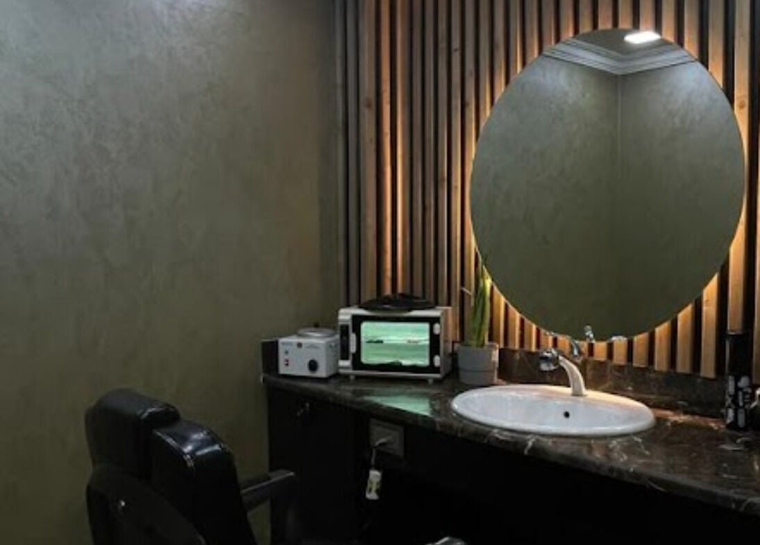 Elegant salon setup at Dark Candles Saloon, Abu Dhabi, AE., featuring modern decor and a round mirror.