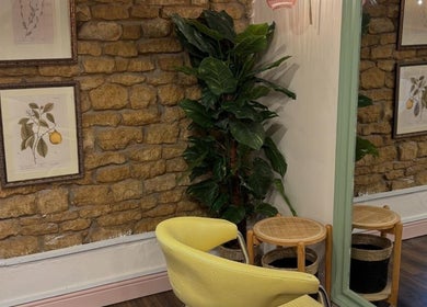 Cozy room at Nicole at Sage and Blush in Grantham, England, GB. Features yellow chair, plant, and stone wall decor.