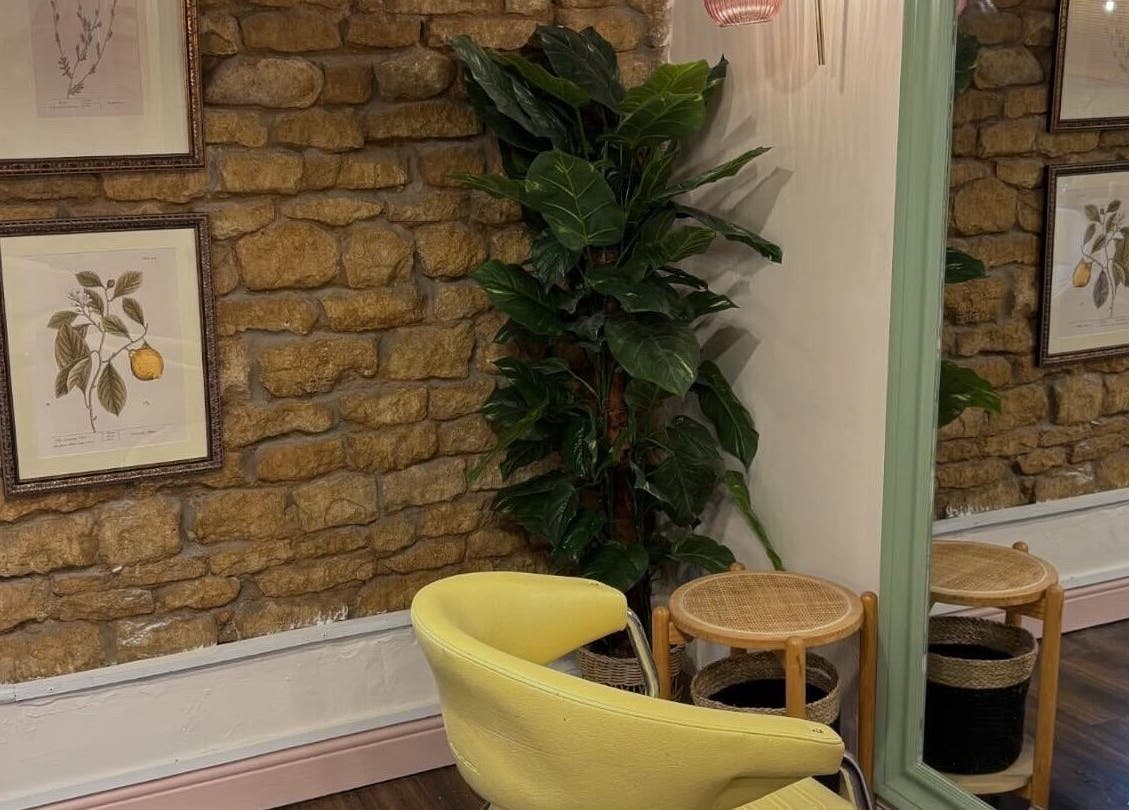 Cozy room at Nicole at Sage and Blush in Grantham, England, GB. Features yellow chair, plant, and stone wall decor.