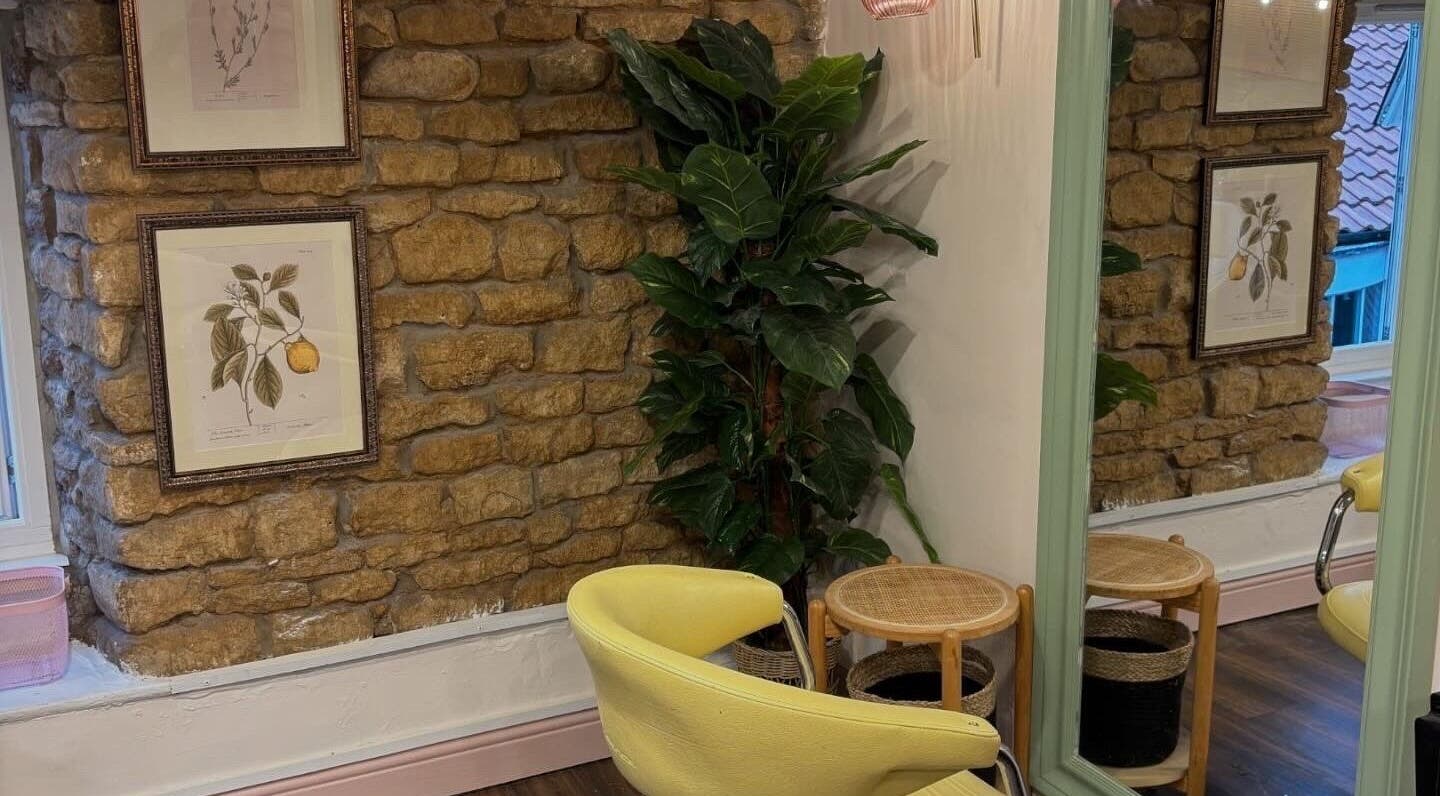 Cozy room at Nicole at Sage and Blush in Grantham, England, GB. Features yellow chair, plant, and stone wall decor.