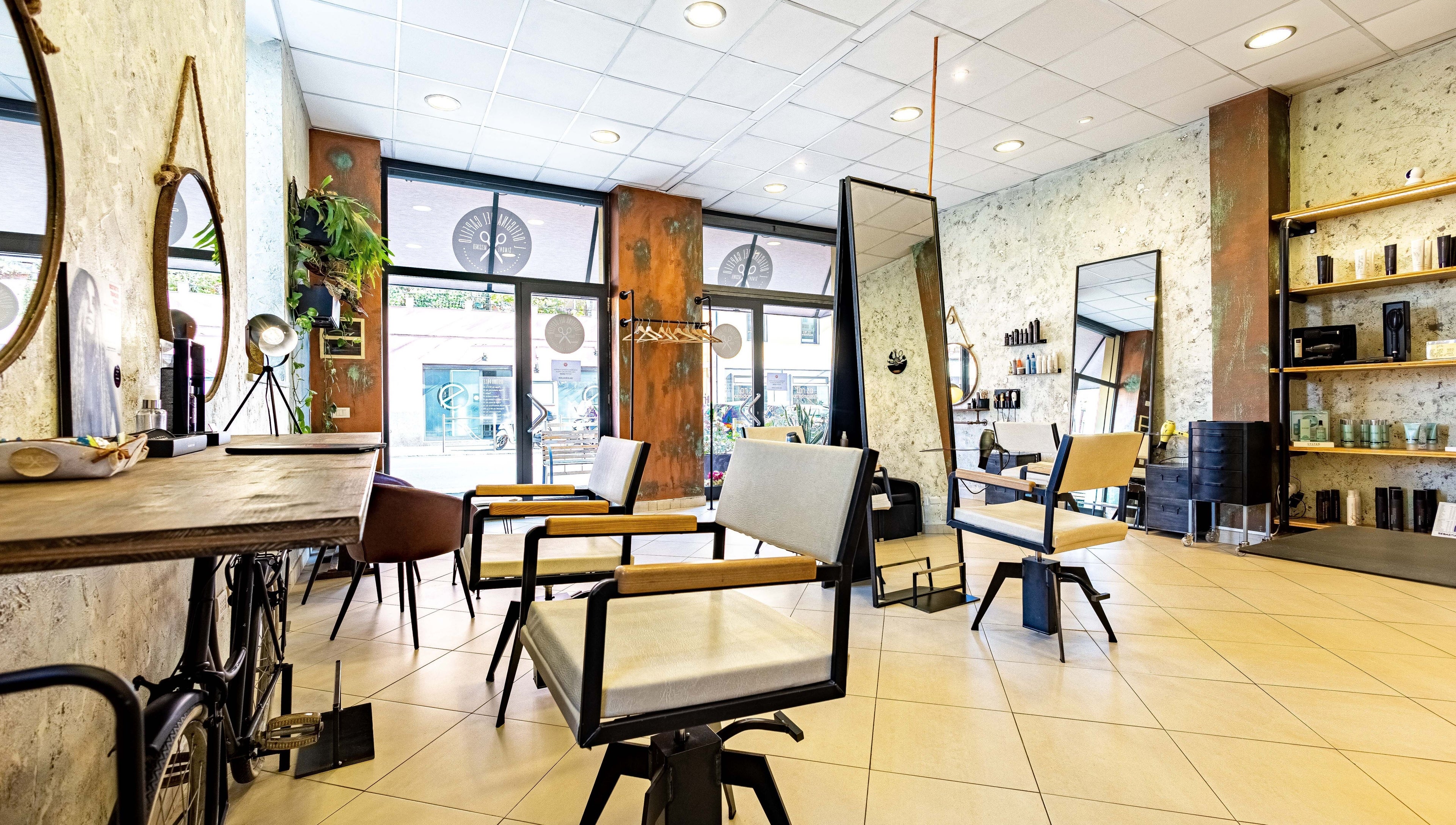 Interno moderno di L’officina Del Capello, Sanremo Liguria, IT, con eleganti sedie e specchi.