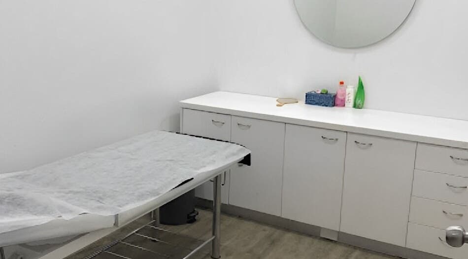 A well-organized treatment room at Beauty Hub in Auckland, Auckland, NZ with a massage table and storage cabinets.