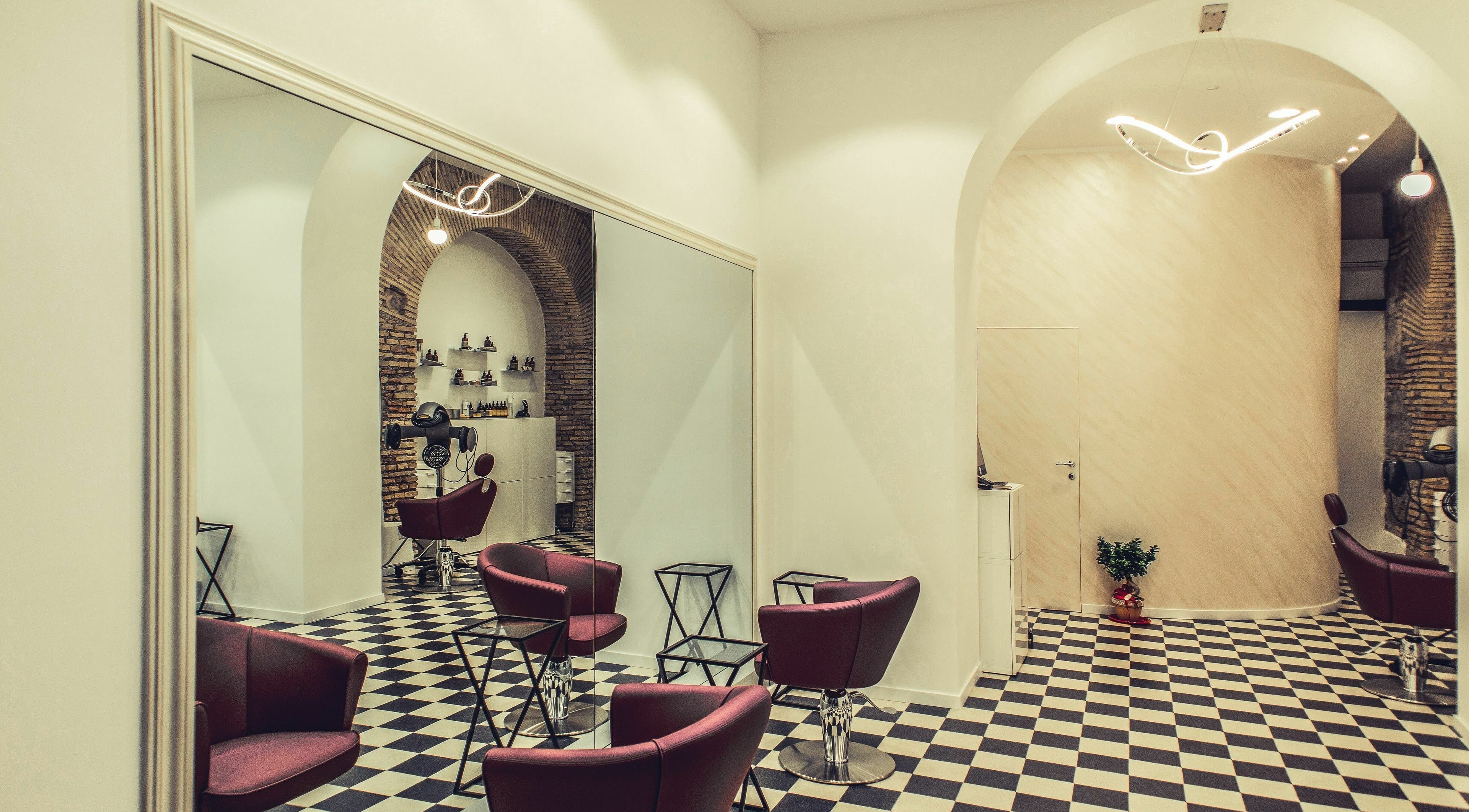 Interno elegante di Grazia Bianchi Hair Spa Couture a Roma, Lazio, IT con poltrone rosse e decorazioni moderne.
